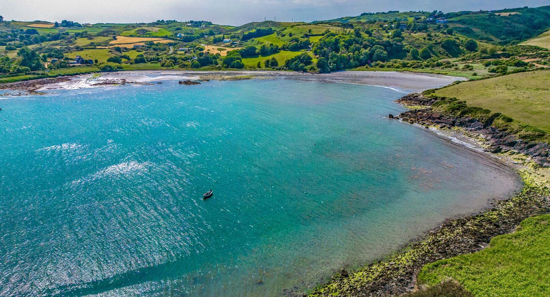 Drone shot of bay showing blue water and surrounding fields